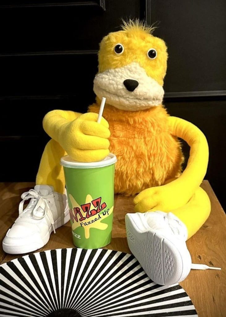 Flat Eric игрушка на заказ держит стакан с трубочкой, рядом белые кроссовки