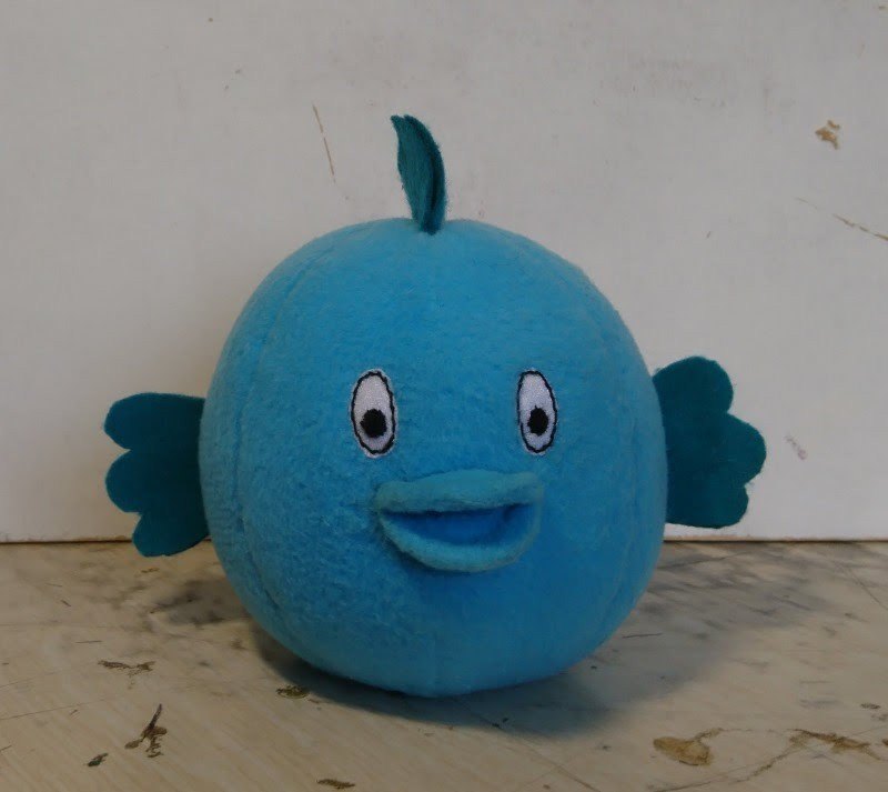 Плюшевая рыба ручной работы в мастерской: бирюзовый шар с открытым ртом и волнистыми боковыми плавниками